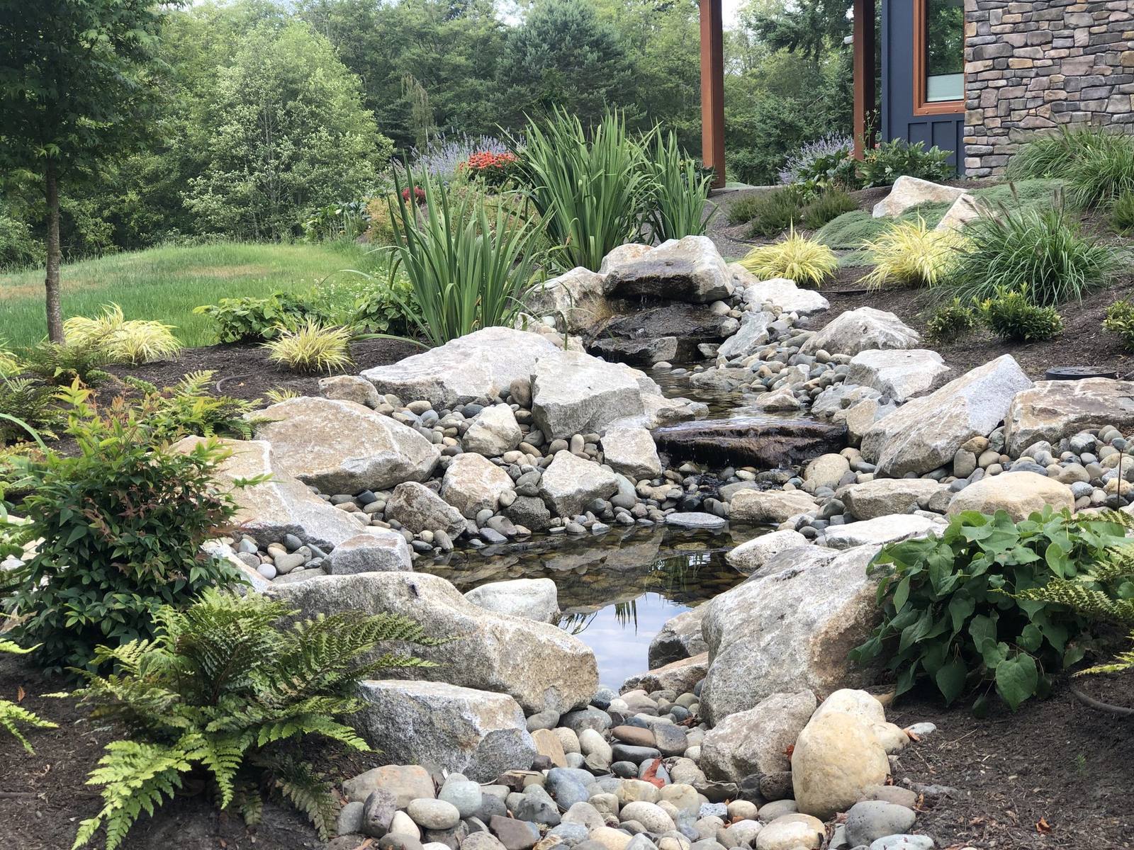 Natural stone pond and cascade set into a lush garden