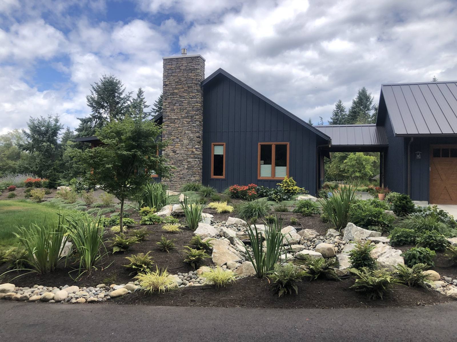Modern country home with stone chimney and naturalistic stream garden