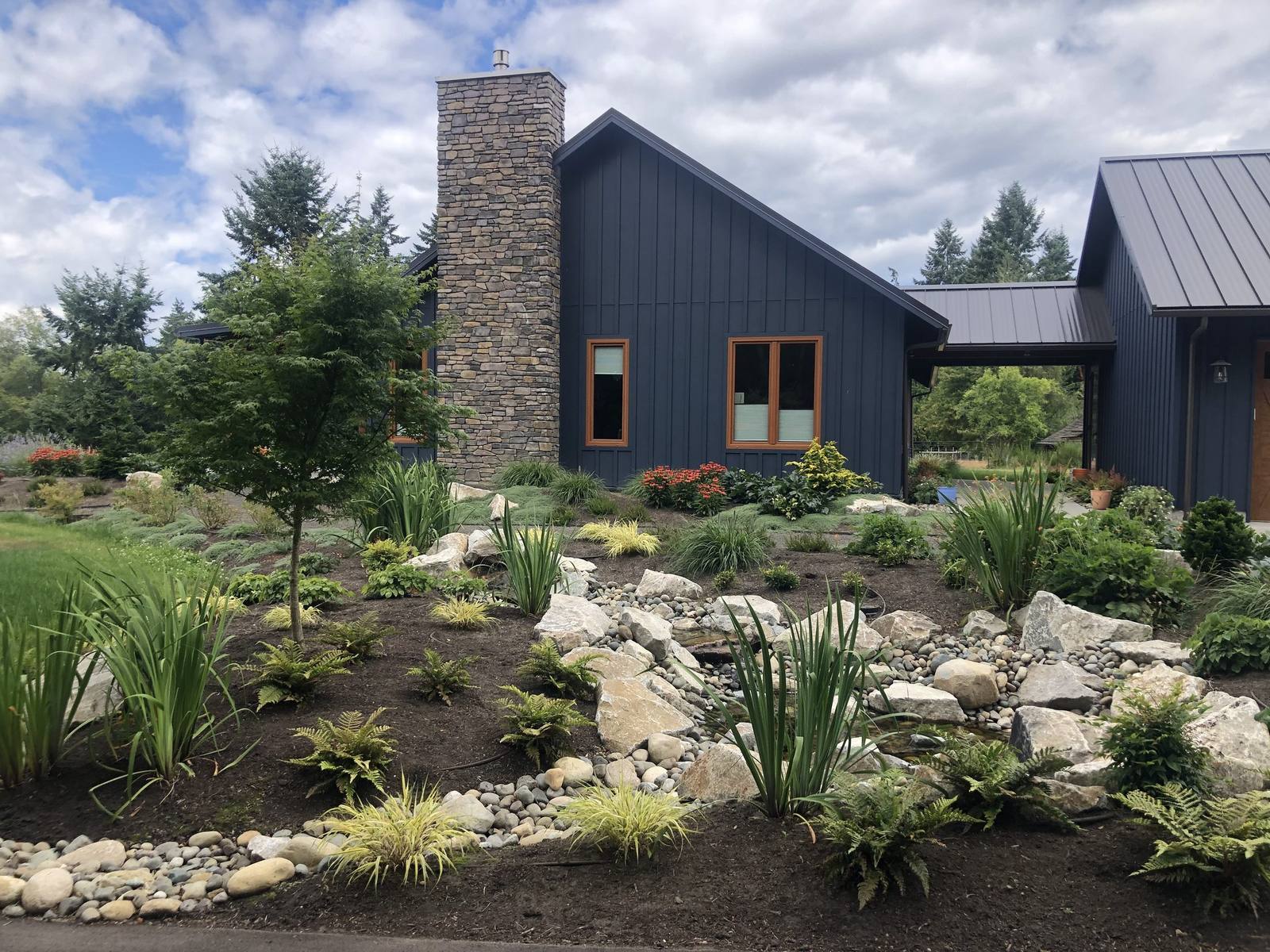 Broad view of the modern home and rock-lined water garden