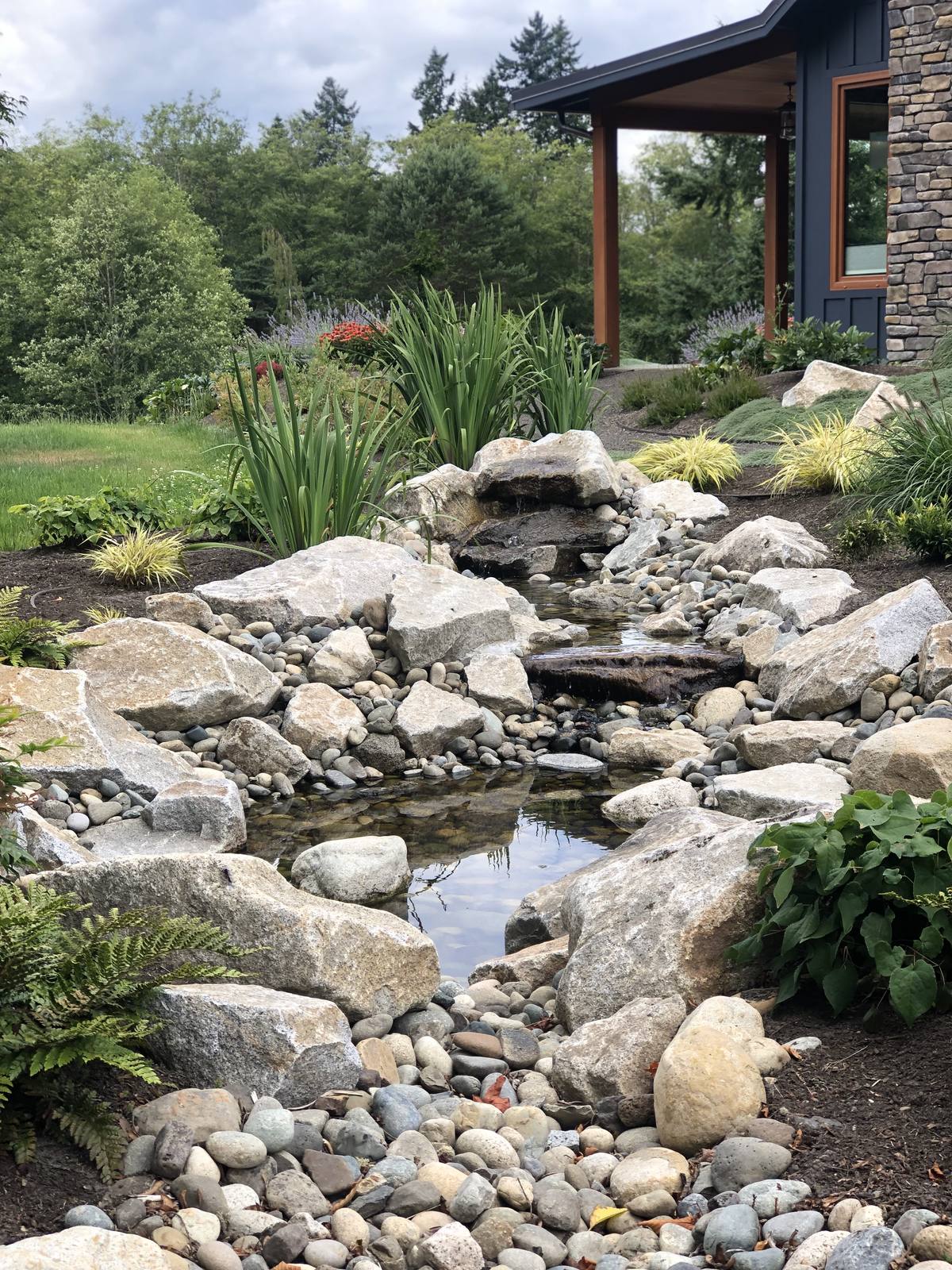 Natural stone stream flowing through the garden beside a modern home