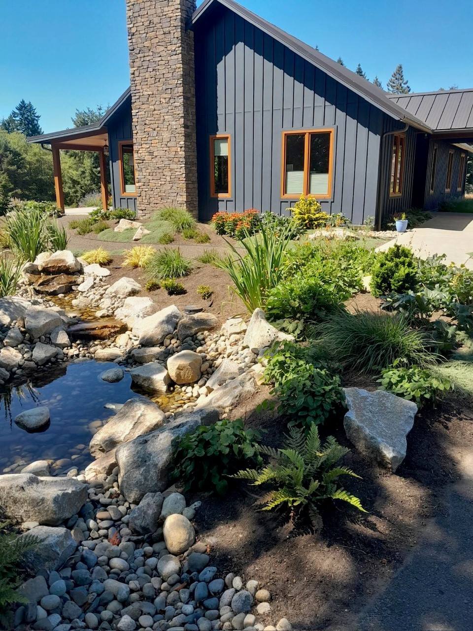 Completed natural stone stream and pond beside a modern home